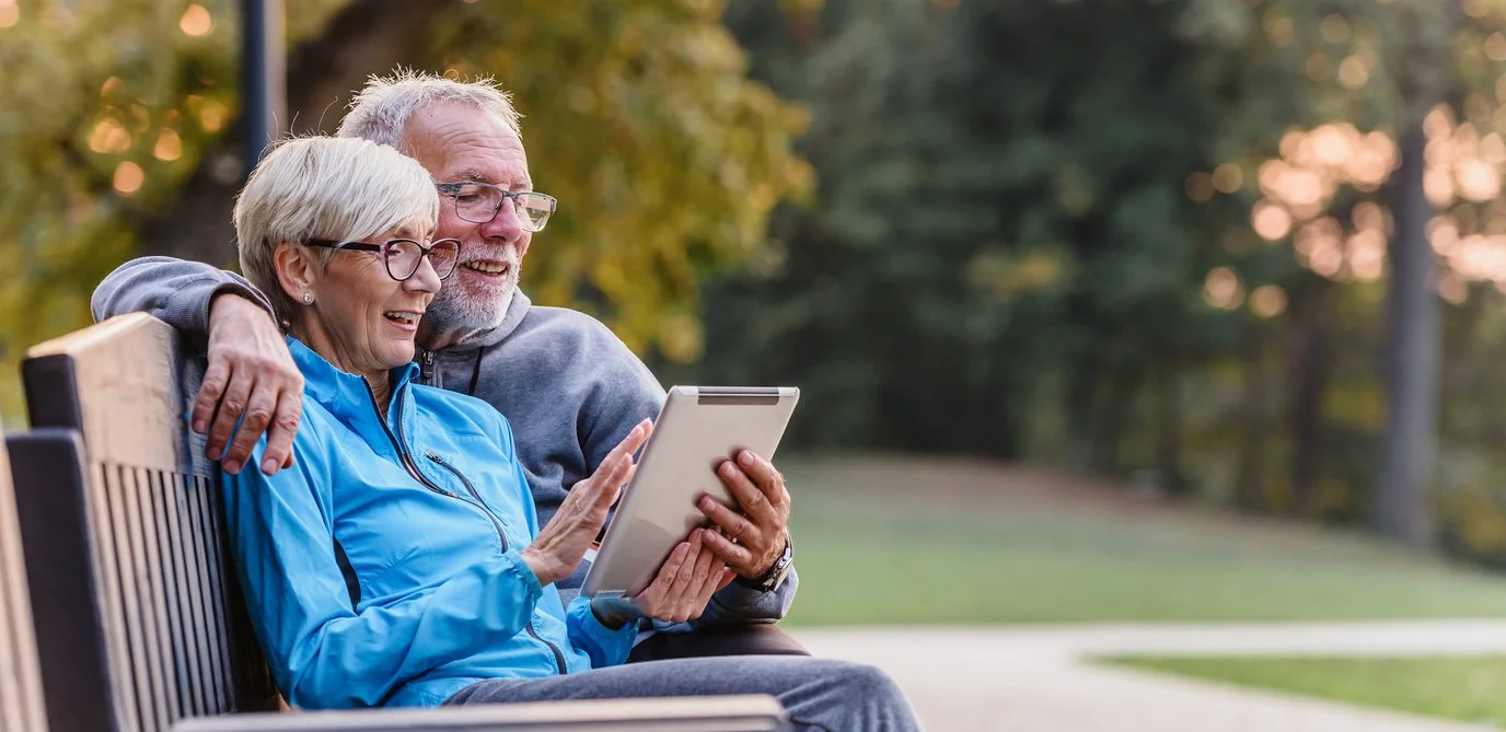 Couple reads tablet on park bench