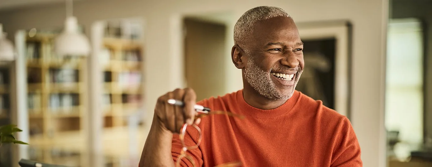 A smiling Clover member in an orange sweater looking over his plan guide at home