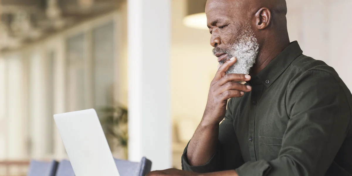 Older man in a green shirt using laptop computer at a workspace