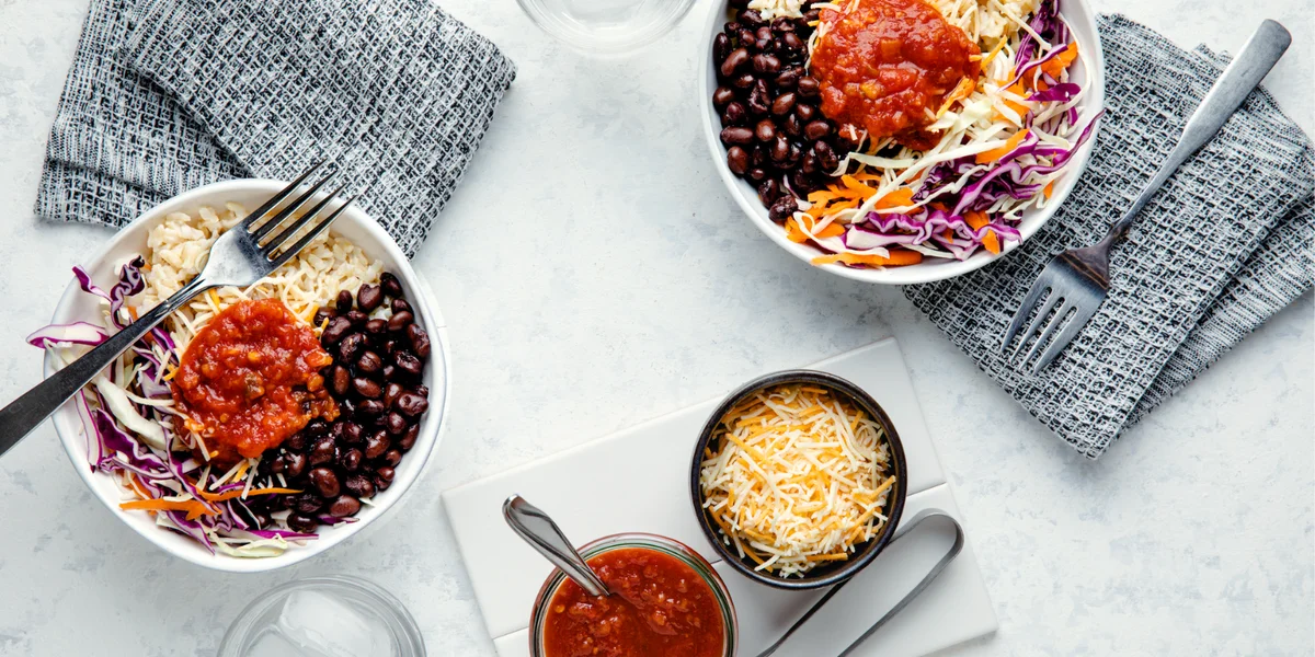 Two bowls of Tex-Mex Black Bean Bowls on a marble table.