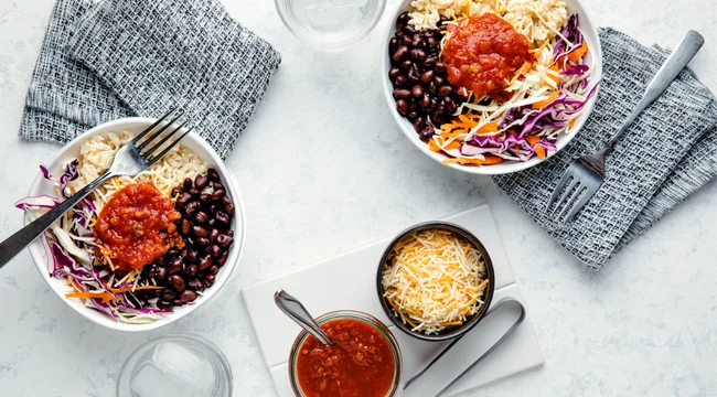 Two bowls of Tex-Mex Black Bean Bowls on a marble table.