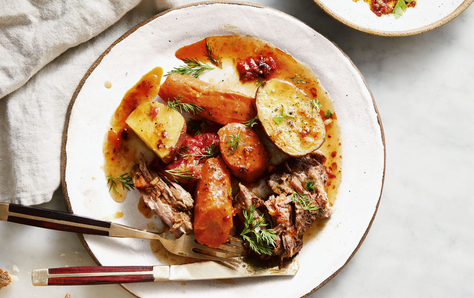 vegetable pot roast with potatoes on a plate with a fork and knife