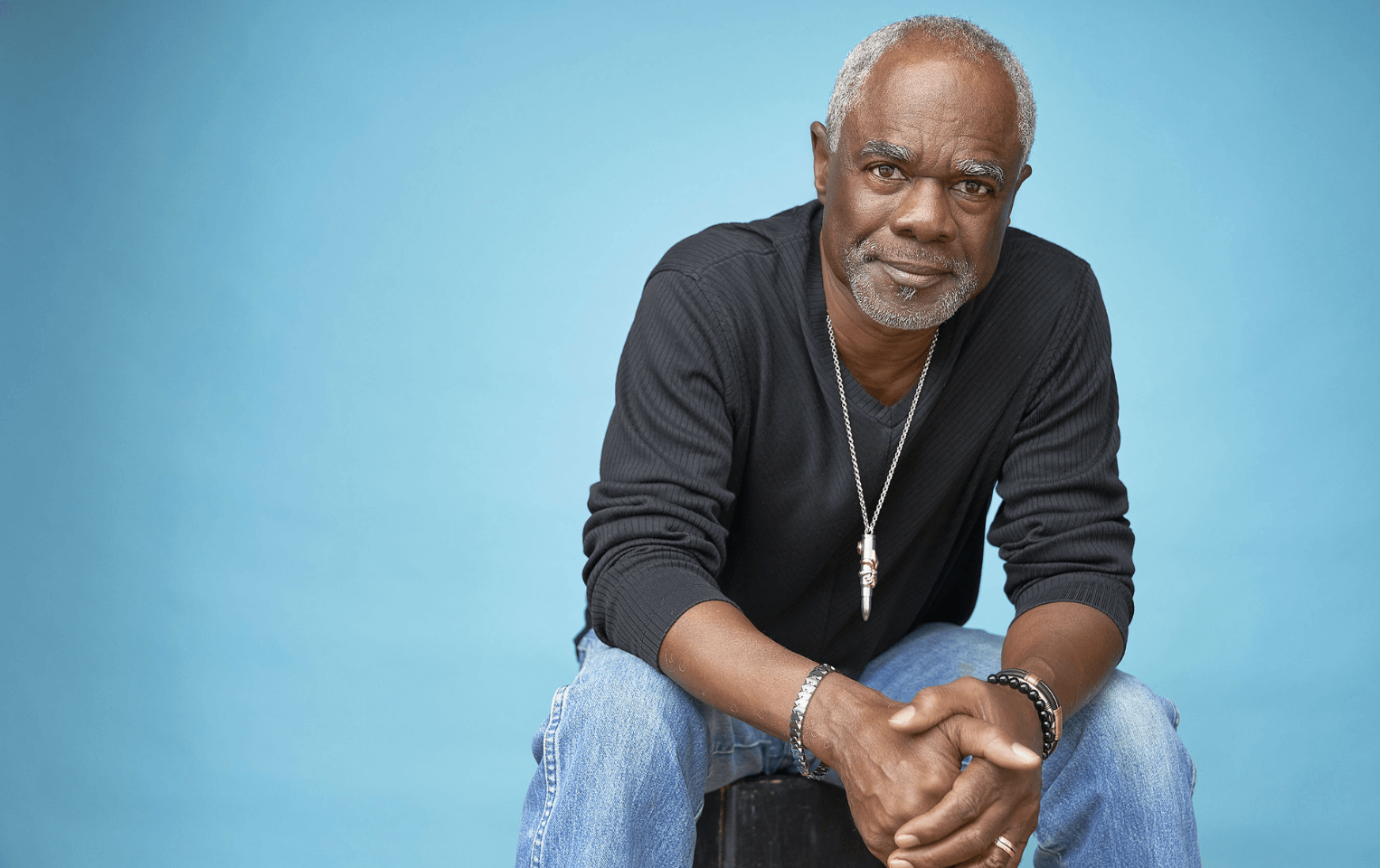 Actor Glynn Turman sitting on a stool in front of a blue background