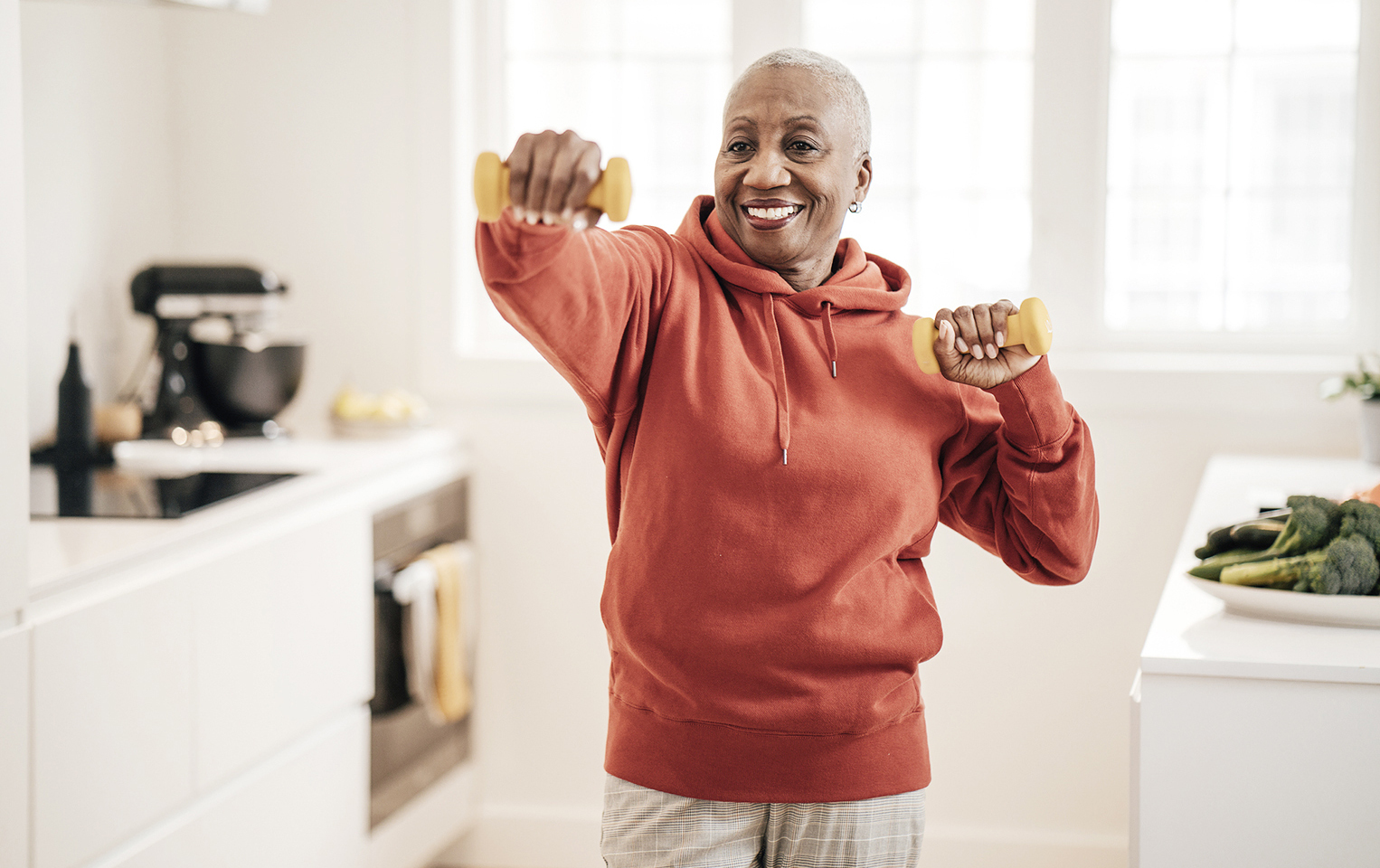 person in their kitchen holding weights doing an exercise