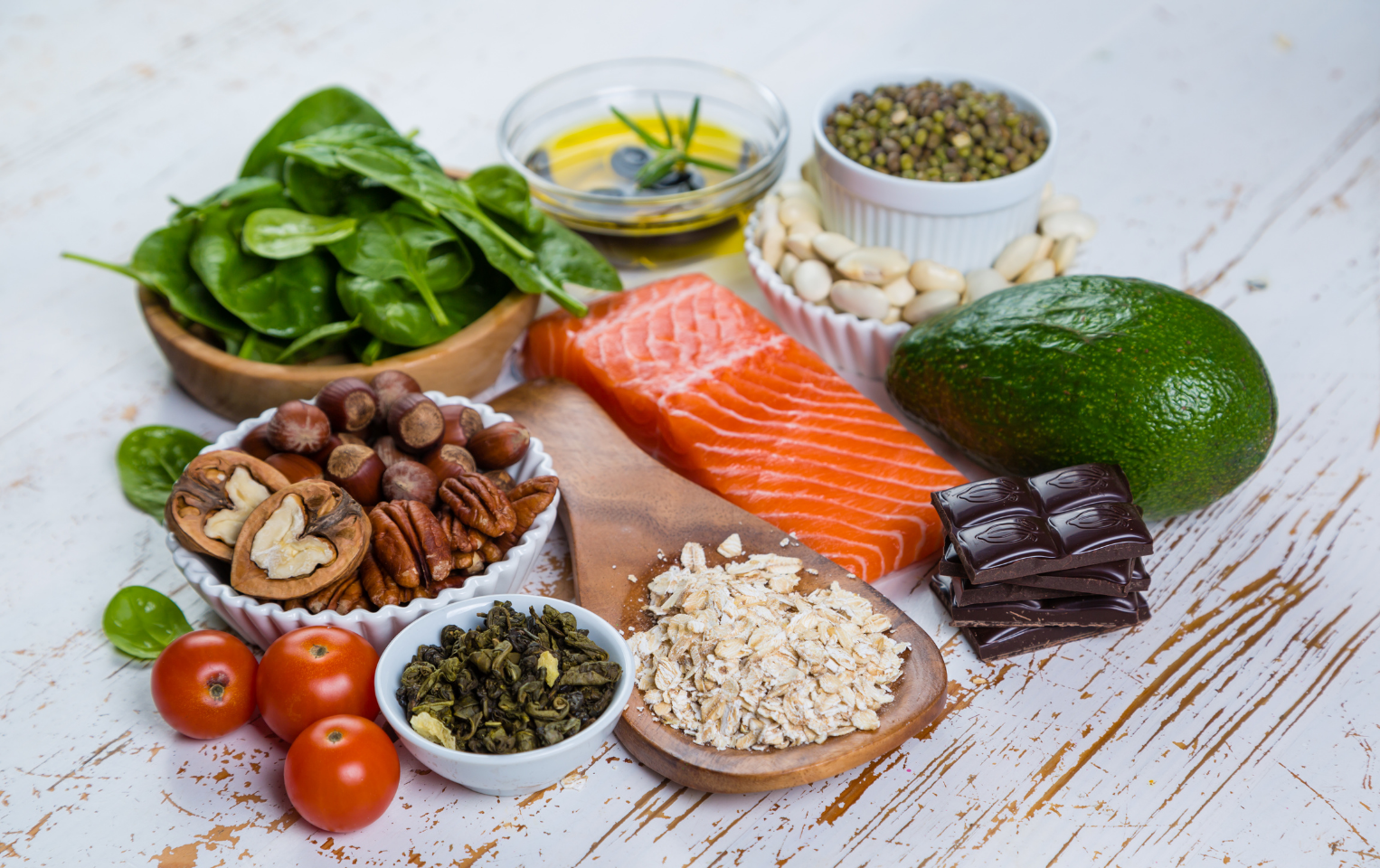 Variety of nutritional food such as salmon, avocado, spinach tomatoes, and grains on a table.