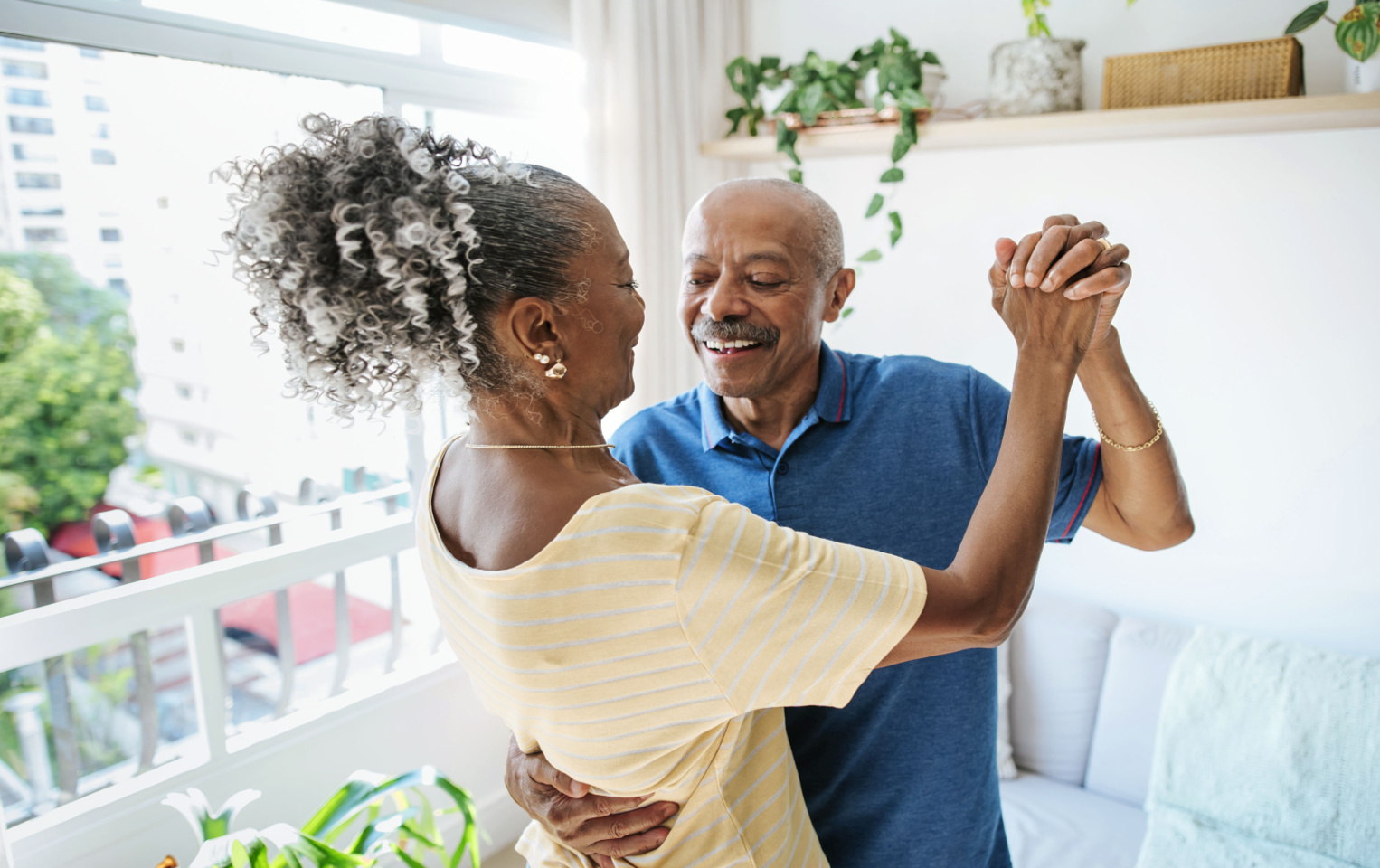 A woman in a yellow shirt and a man in a blue polo dancing in the living room