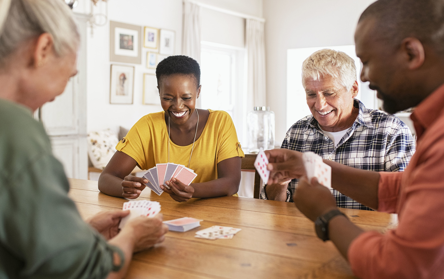 Group of 4 friends sitting at a table playing cards