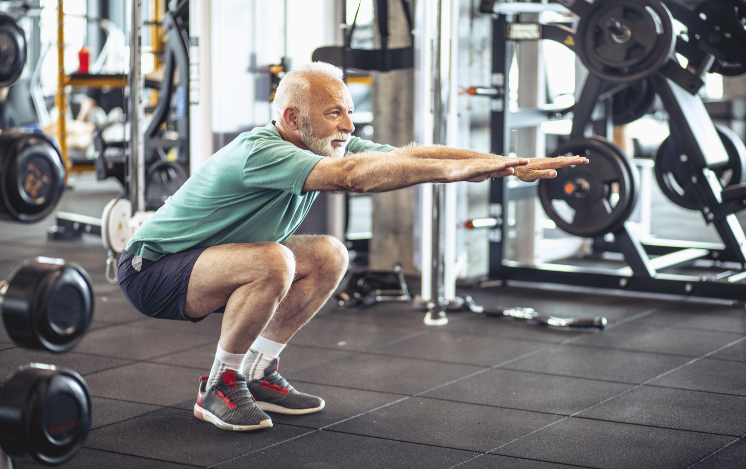 Man in a green shirt doing squats at the gym