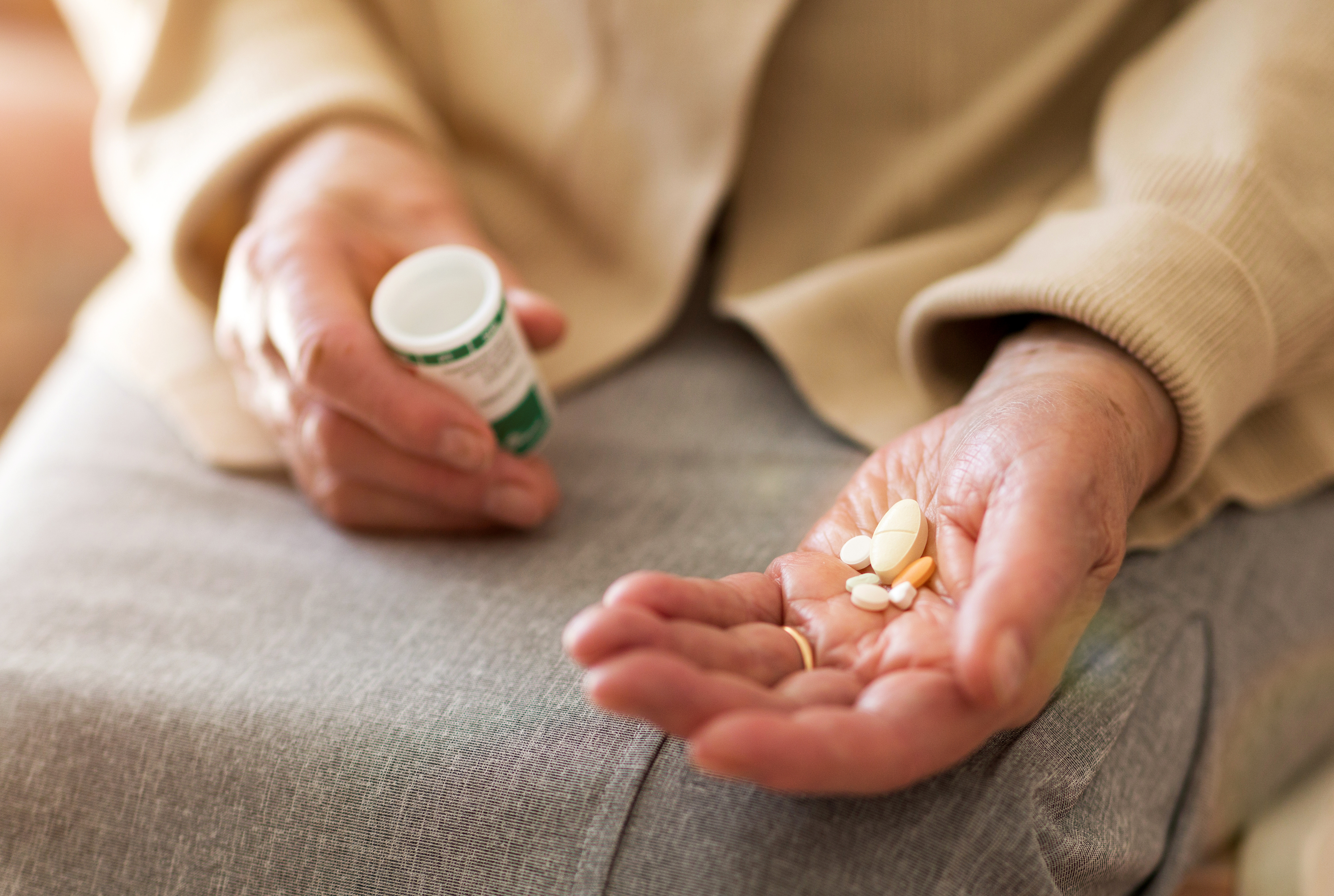 Person holding medication in one hand with the prescription bottle in the other hand