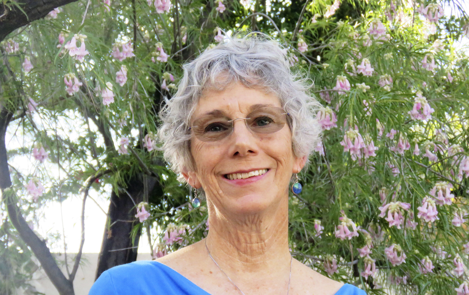 photo of Kathy McIntosh standing in front of a blooming tree