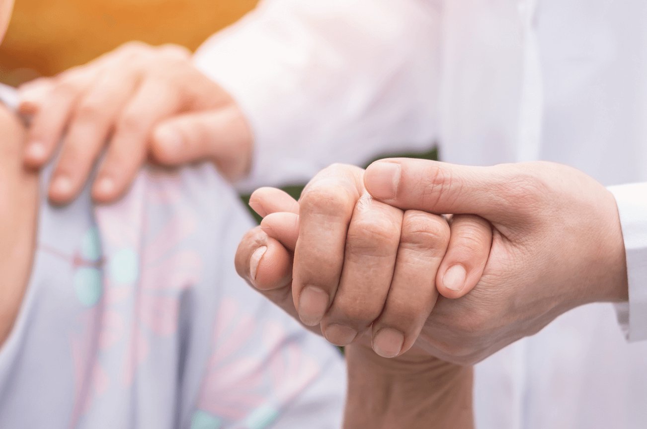 doctor holding an Alzheimer’s patient’s hand and comforting them