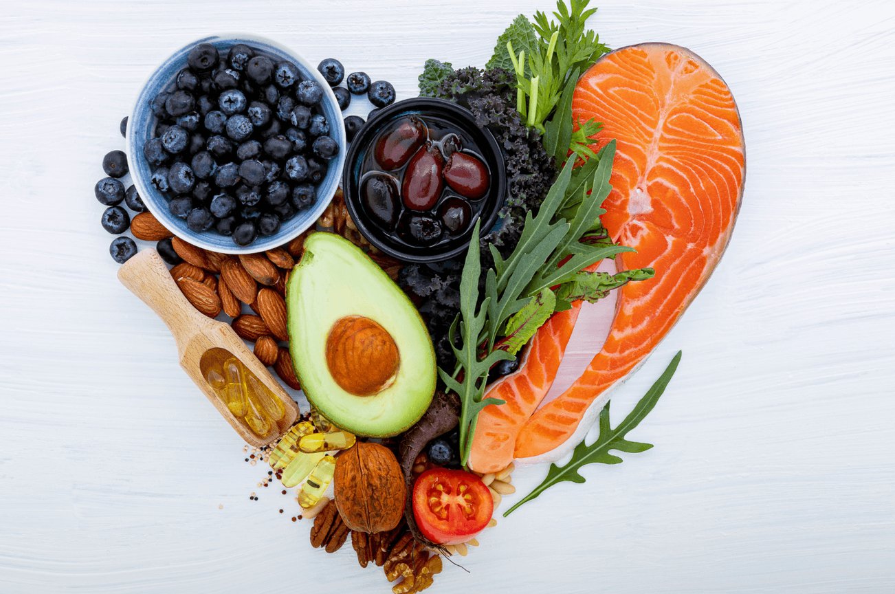heart made out of different heart-healthy foods, including blueberries, salmon, avocado, and leafy greens