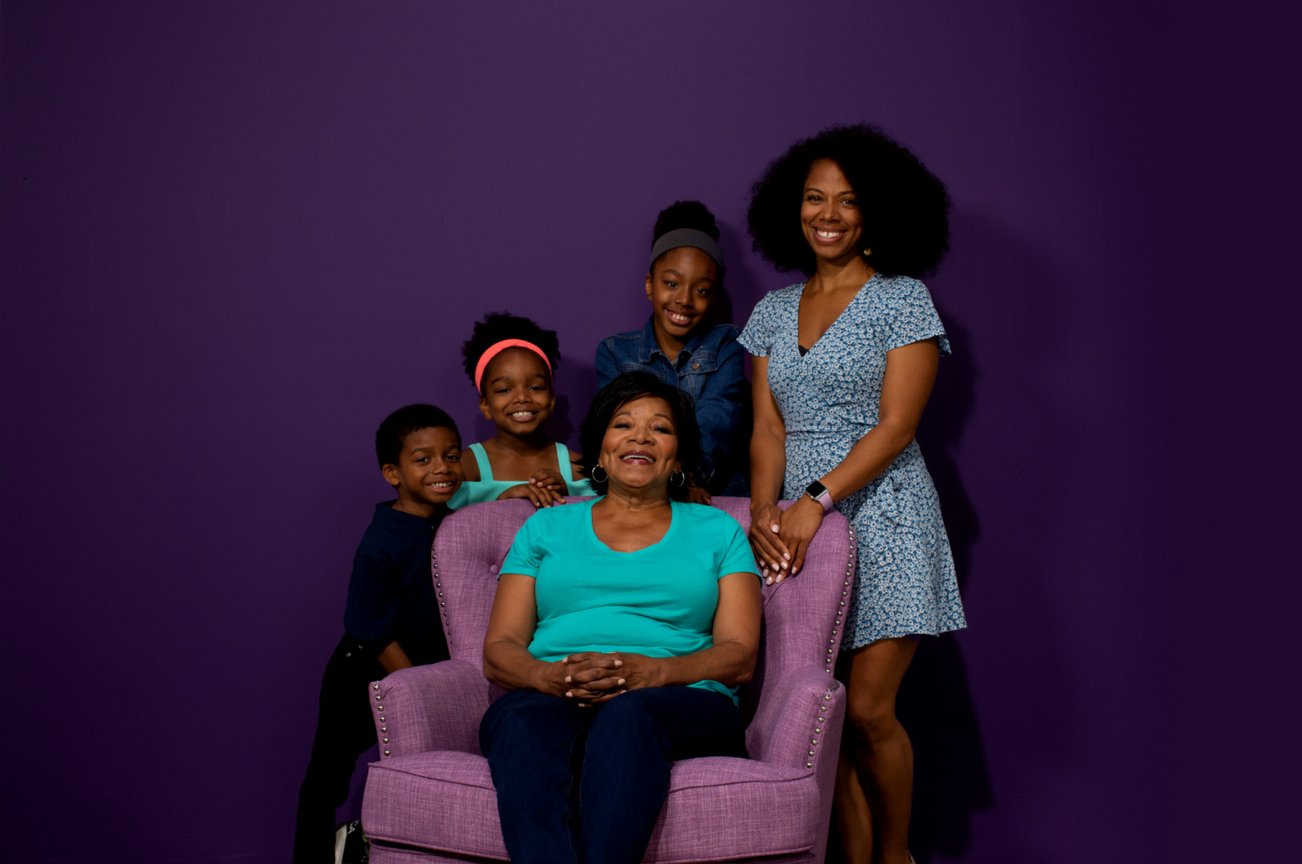 Charylee sitting in a chair surrounded by her family