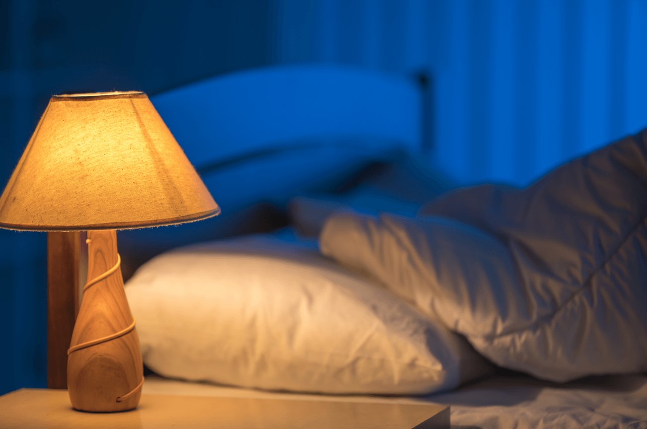 bedroom at night time with a lamp turned on on the nightstand